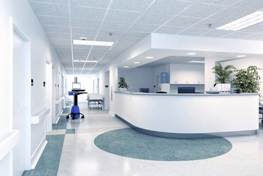 Bright, modern hospital reception with a curved white desk, teal floor accent, medical equipment, plants, and a clean, welcoming atmosphere.