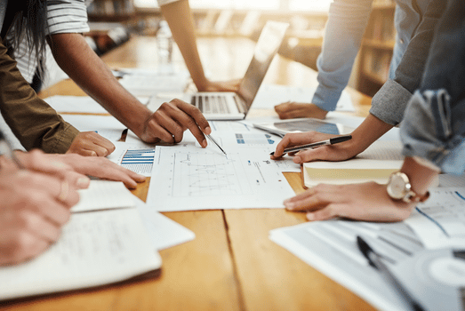 Diverse team collaborates around a table, reviewing blueprints and plans in a bright office, conveying teamwork and creativity. energy efficiency for operating companies