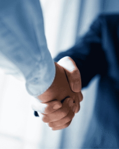 Close-up of two professionals shaking hands, symbolizing agreement and partnership, with cool blue lighting and a confident business tone.